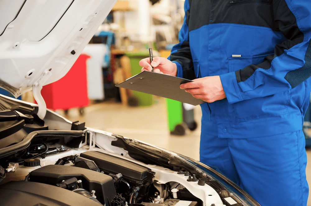 Man assesses the condition of the car by looking under the bonnet