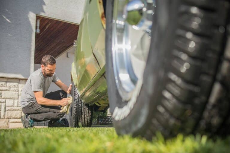 Man performing a basic car service check on a tyre before deciding to sell my car online.